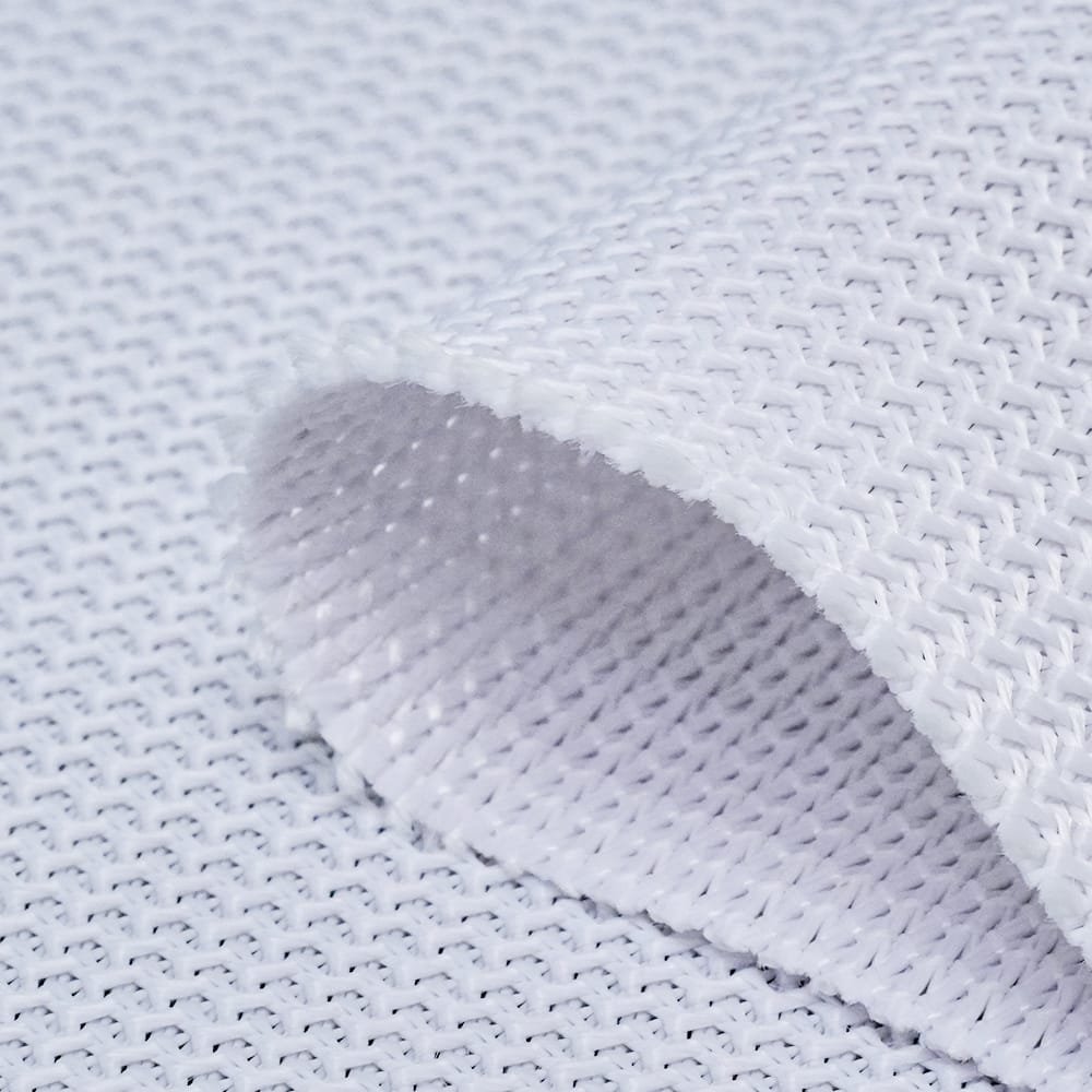 Curled edge of white golf screen material showing the surface and cut edge